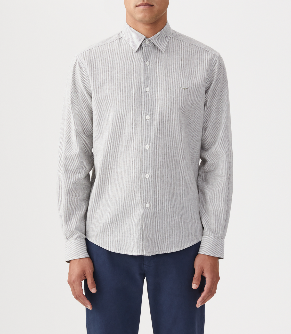 A person wears the RM Williams Coalcliff Shirt in light gray with long sleeves and dark blue pants, standing against a plain white background. The shirt has a small embroidered logo on the left chest.