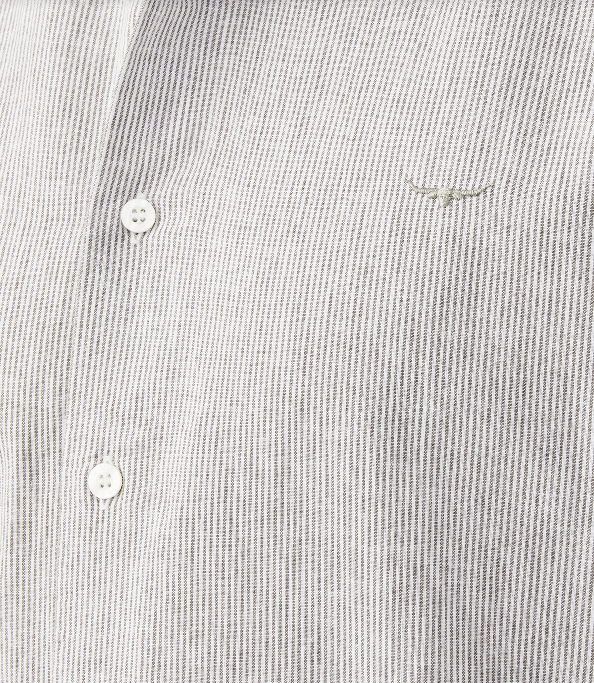 Close-up of an RM Williams Coalcliff Shirt in light grey with stripes, featuring three white buttons and thin vertical lines. A small longhorn embroidery resembling a bull's head adds a unique touch to the upper right of this classic shirt.