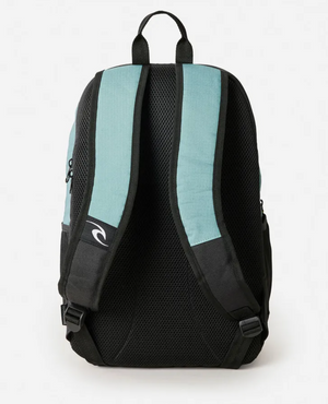 The Rip Curl Ozone 2025 School 30L Backpack in teal and black is shown from the back, featuring padded mesh shoulder straps, a small white wave logo on the left strap, a sturdy top handle, and an ergonomic back panel—ideal for school.
