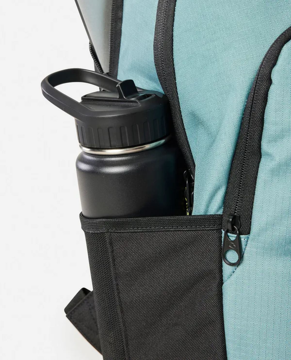 A close-up of a teal Rip Curl Ozone 2025 School 30L Backpack with a black zipper, featuring a black water bottle in the outer side pocket.