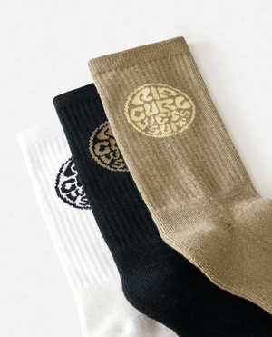 The Rip Curl Wetty Crew Sock 3 Pack includes three pairs of ribbed crew socks in white, black, and tan, made from a soft acrylic blend with circular logos near the cuff, designed for all-day comfort.