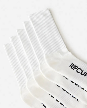 Five pairs of white Rip Curl School Crew Socks are stacked diagonally, toes pointing right. The black "RIP CURL" logo appears on the top sock near the toes, showcasing their terry footbed and built-in arch support.