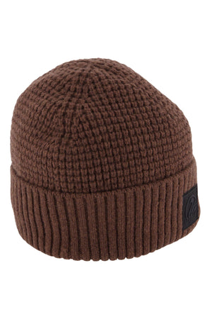 The Swanndri Newton Beanie is a brown waffle knit hat featuring a folded brim and a black patch on the side.