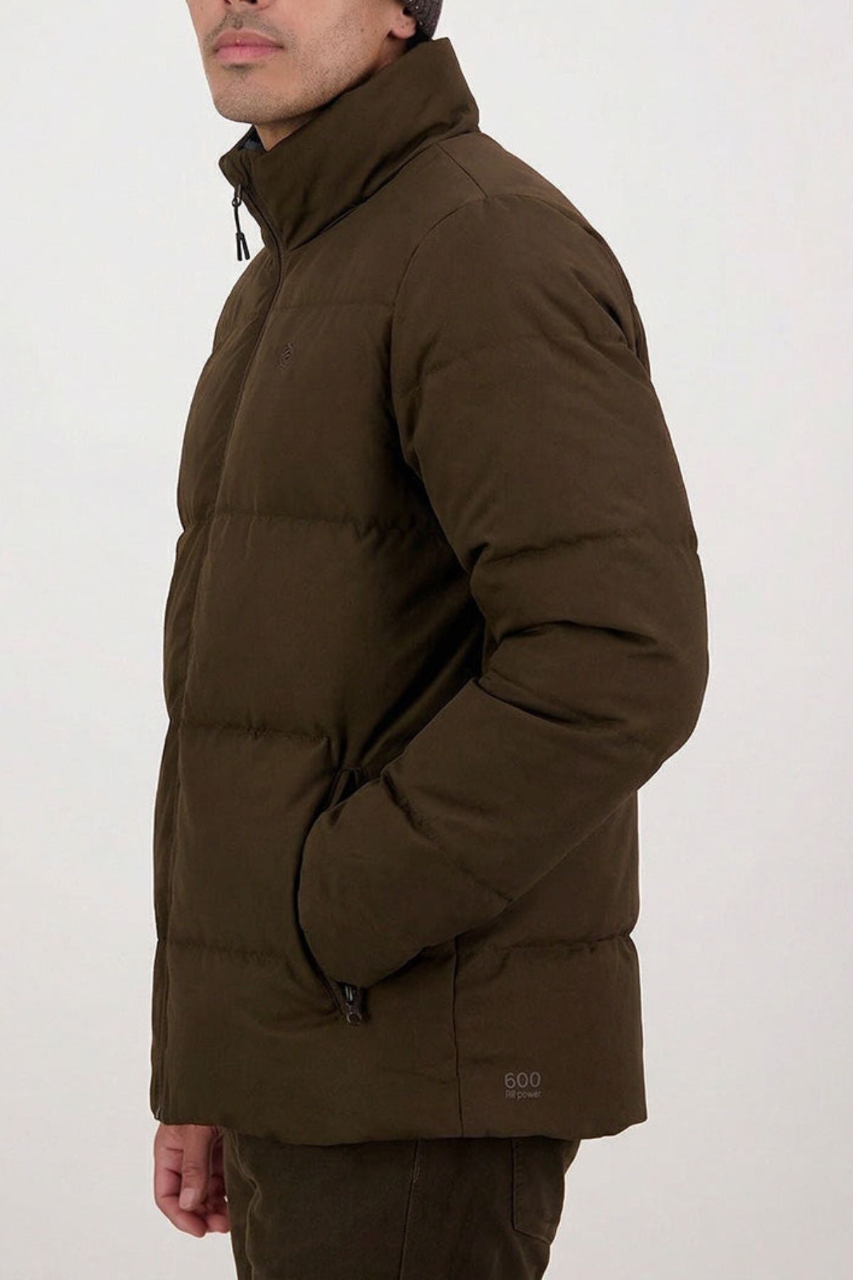 A person models the Swanndri Nimbus Down Jacket, standing sideways with hands in the pockets against a plain light background, showing only the lower half of their face.
