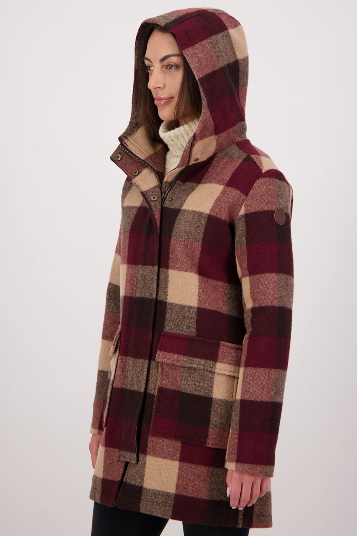 Dressed in a Swanndri Annmore V2 Wool Overcoat with a large burgundy, brown, and beige check pattern over a white turtleneck, a person stands against a plain light background.