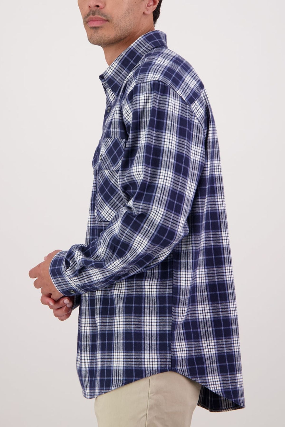 A person wears the Swanndri Barn Shirt in blue and white plaid with beige pants, standing sideways against a plain light background—a classic heritage look ideal for winter layering.