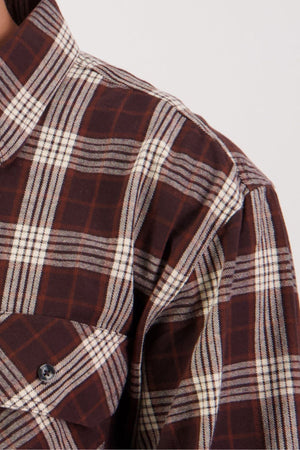 Close-up of the Swanndri Barn Shirt in brown plaid flannel with white and dark stripes, featuring the collar, shoulder, chest pocket, and visible buttons—ideal for heritage looks and winter layering.