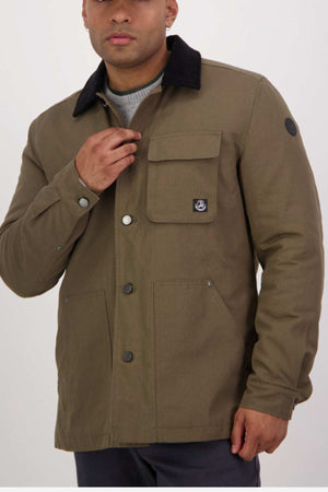 A person in a rugged green Swanndri Barrytown v3 Canvas Work Jacket, featuring a black collar, chest pocket with patch, and visible buttons, stands against a plain white background.