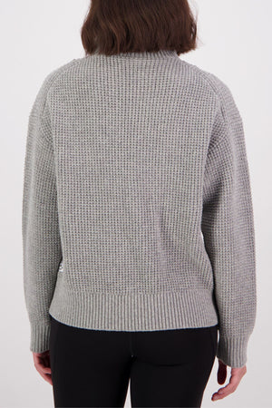 A person with shoulder-length brown hair is seen from behind wearing a gray Swanndri Darlinghurst Zip Jumper and black pants against a plain white background.