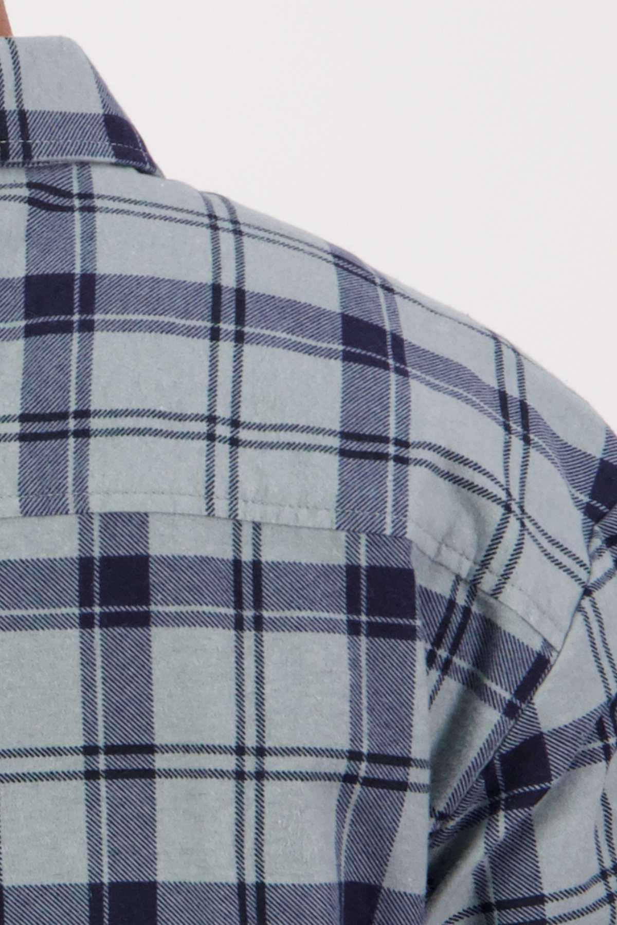 Close-up of a person wearing a Swanndri Egmont Flannelette shirt in blue and gray plaid. The image focuses on the upper back and shoulder area, highlighting the pattern and texture of the brushed cotton fabric.