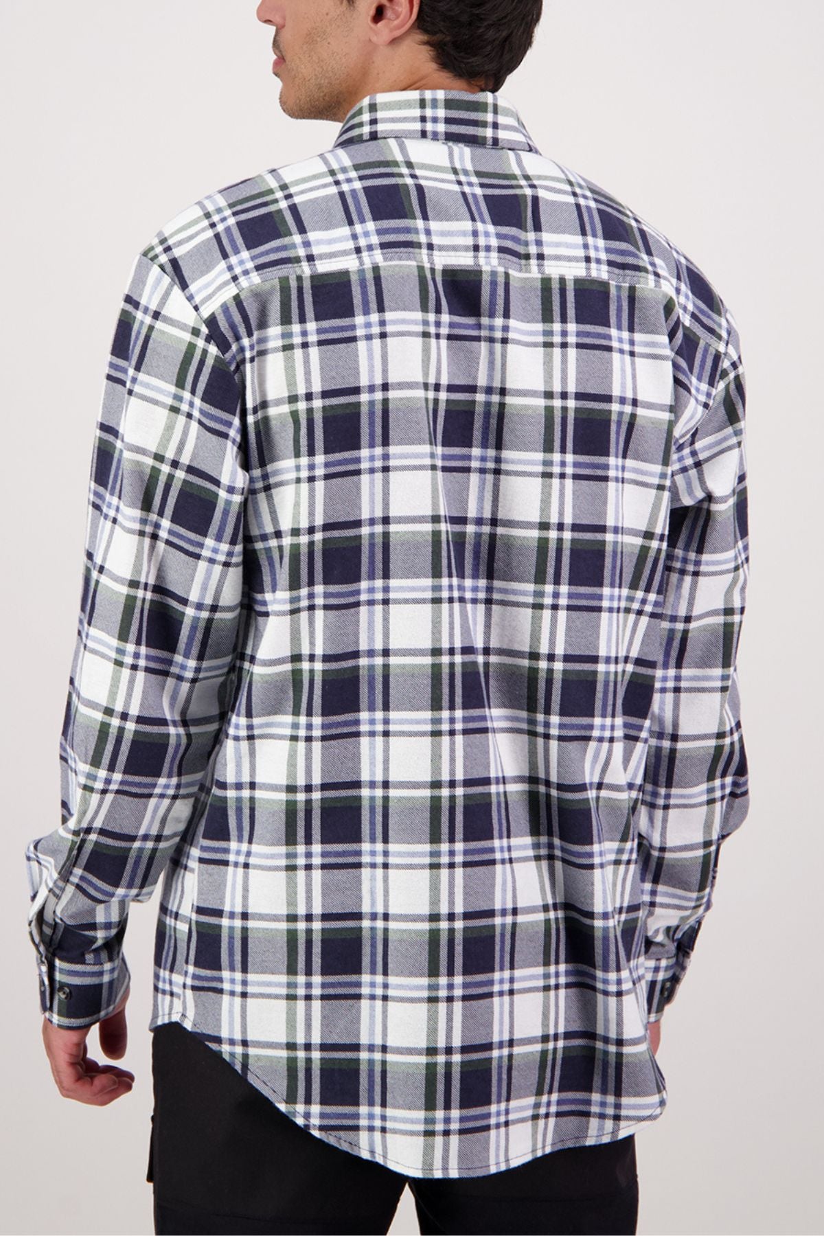 A man with short dark hair stands against a plain light background, wearing the Swanndri Egmont Flannelette Twin Pack—a long-sleeve, button-up shirt featuring a blue, green, and white plaid pattern.