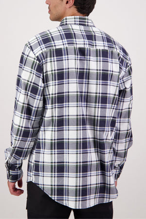 A man with short dark hair stands against a plain light background, wearing the Swanndri Egmont Flannelette Twin Pack—a long-sleeve, button-up shirt featuring a blue, green, and white plaid pattern.