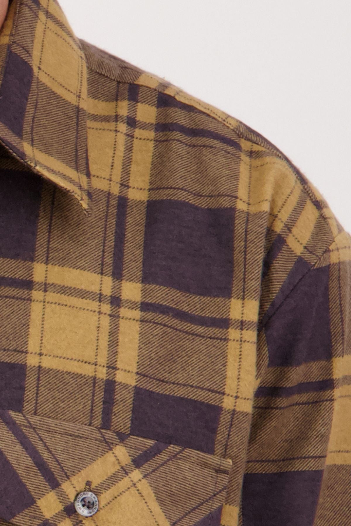 Close-up of the Swanndri Egmont Flannelette Twin Pack shirt in yellow and dark purple plaid, highlighting the collar, shoulder, pocket, and a button.