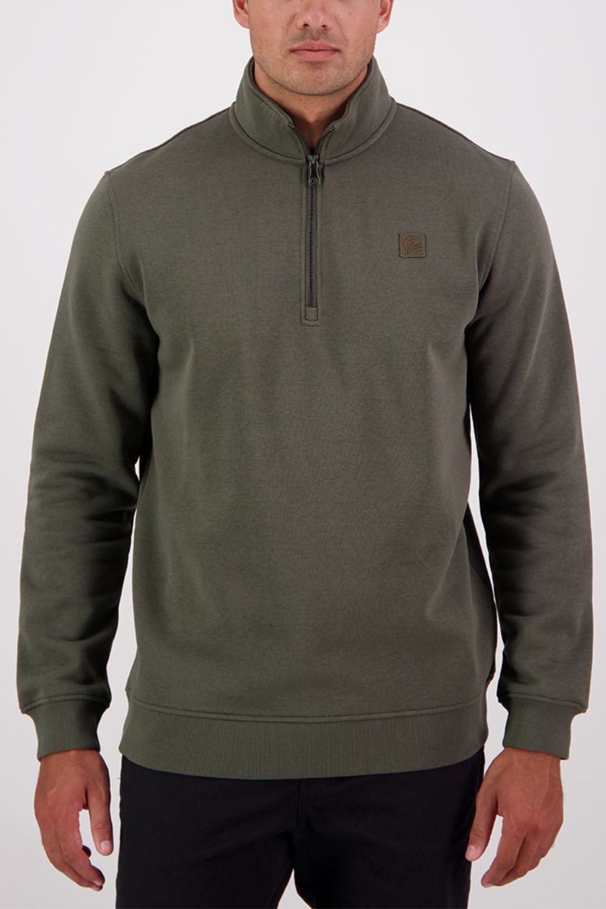 A man wears the Swanndri Fundamentals Quarter Zip in olive green, made from recycled polyester and featuring a small square logo on the left chest, standing against a plain white background.