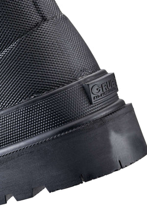Close-up of a sturdy black Grubs Fenline High Work Boot with a textured surface, showcasing a thick sole and part of the heel. The brand "Grubs" is embossed on the side. The design features durable neoprene material and superior grip, suggesting the boot is intended for heavy-duty or outdoor use.