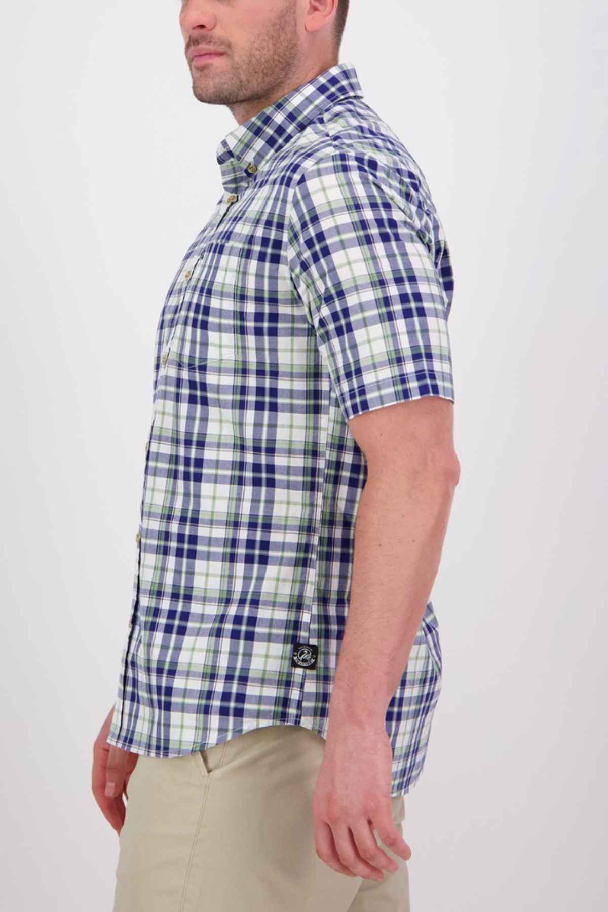 A person wearing a blue and white plaid Swanndri Herbert Short Sleeve Shirt with a tailored fit and khaki pants stands in profile against a plain background.