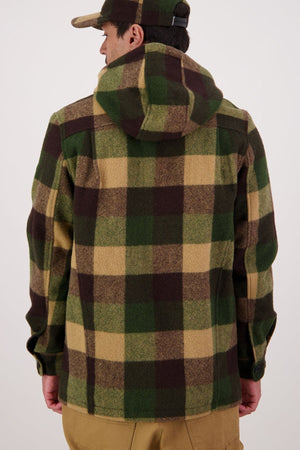 Facing away, a person wears the Swanndri Hudson Hoodie—a green, brown, and beige plaid New Zealand wool jacket—and a matching cap with tan pants, standing out against a plain light background.