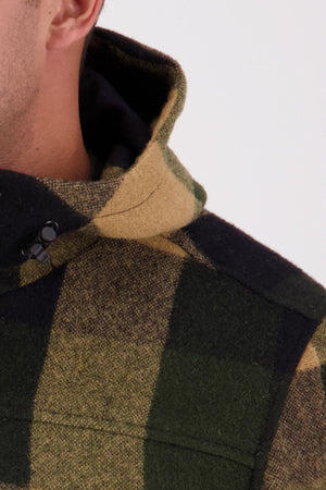 Close-up of a person wearing the Swanndri Hudson Hoodie in green, yellow, and black New Zealand wool; only part of their jaw, ear, and shoulder visible against a plain light background.