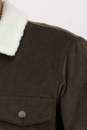 A close-up of the Swanndri Kaituna Corduroy Jacket highlights its green corduroy fabric with a white polyester sherpa-lined collar. The image focuses on the upper section, showing a buttoned pocket and textured design details.