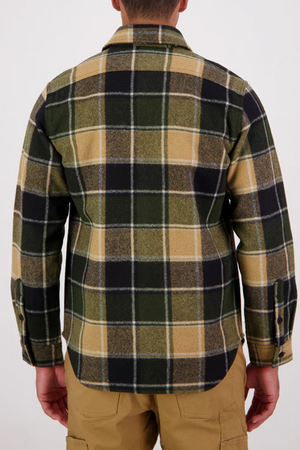 A person is seen from the back wearing the Swanndri Kiaraki v3 Wool Shacket in green, black, and beige with long sleeves, paired with tan pants. The background is plain and light-colored.