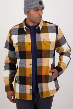 A man in a gray classic fit beanie and a multicolored plaid Swanndri Lowcliffe Shacket made from 100% cotton stands against a plain background, with his navy shirt subtly merging into the scene.