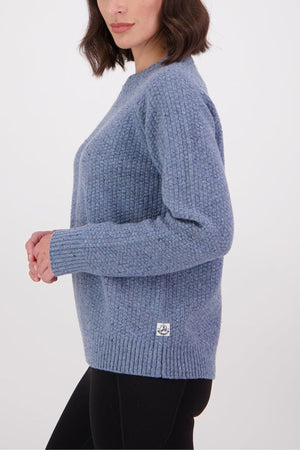 A woman with wavy brown hair models the Swanndri Lyttelton Womens Waffle Crew in light blue with black leggings, standing sideways with her hands slightly raised against a plain white background.
