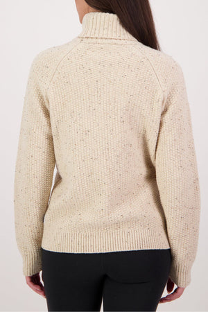A person with long brown hair is seen from the back, wearing a cream Swanndri Lyttelton v2 Roll Neck Knit sweater with a high collar and black pants against a plain, light background.