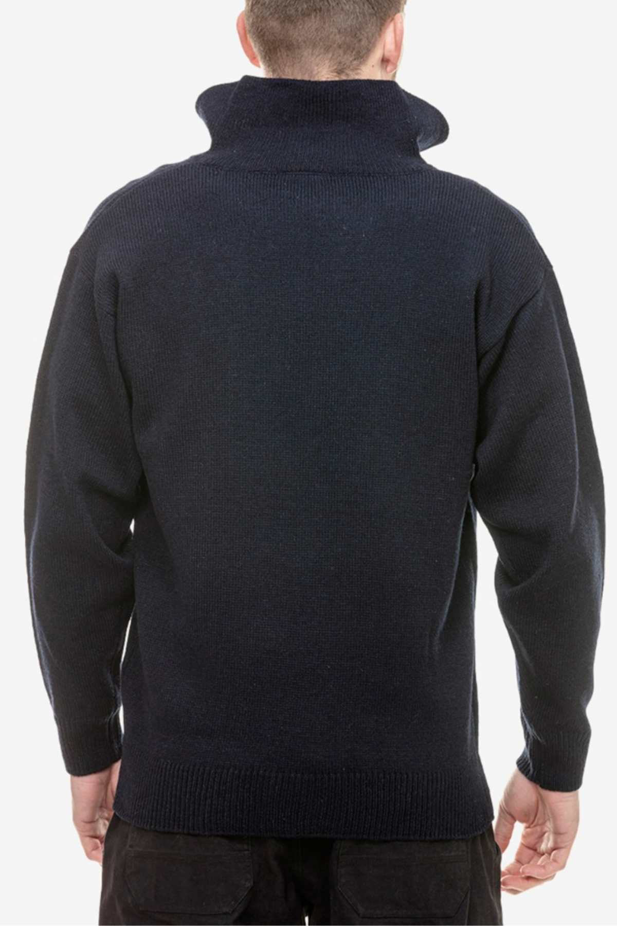A person with short hair is facing away from the camera, wearing a dark navy Swanndri Mariner Zip Neck Sweater. The plain white background emphasizes the stylish knit details of the sweater's ribbed cuffs and hem.