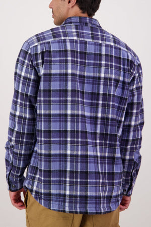 A man is shown from the back against a plain light background, wearing a blue and purple plaid Swanndri Morven Sherpa Shirt with khaki pants.