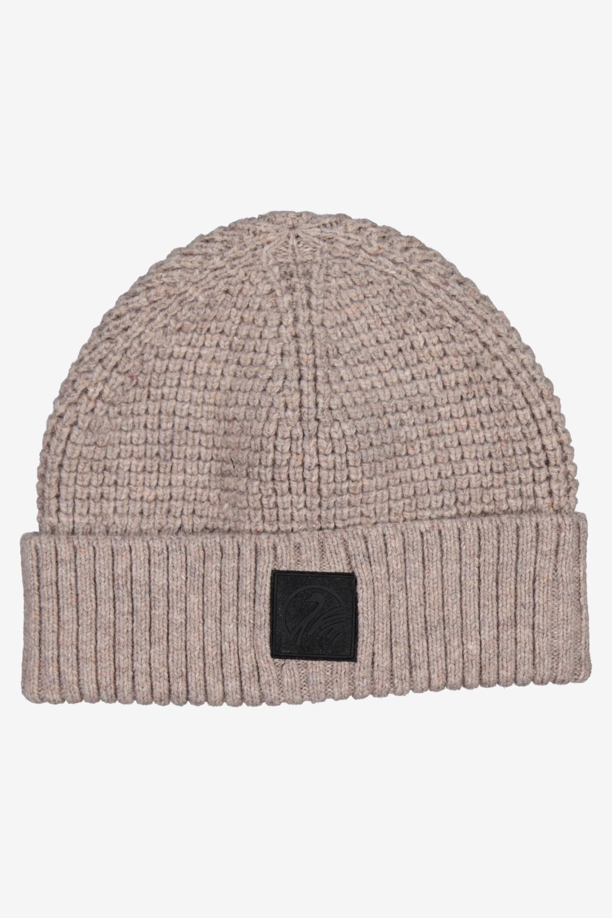 The Swanndri Newton Beanie is a beige waffle knit beanie featuring a folded ribbed brim and a black rectangular patch on the front.