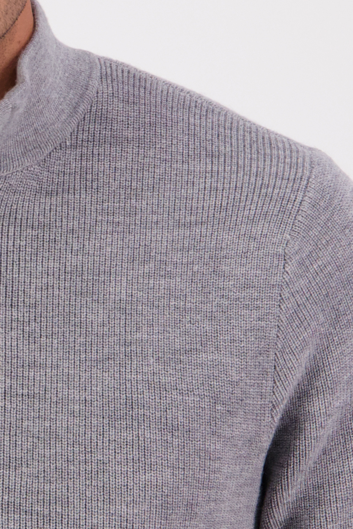 Close-up of a person wearing the Swanndri Otahu River Quarter Zip Merino Knit in light gray, showing only the shoulder, part of the chest, and high ribbed collar against a plain background.