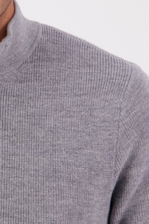 Close-up of a person wearing the Swanndri Otahu River Quarter Zip Merino Knit in light gray, showing only the shoulder, part of the chest, and high ribbed collar against a plain background.