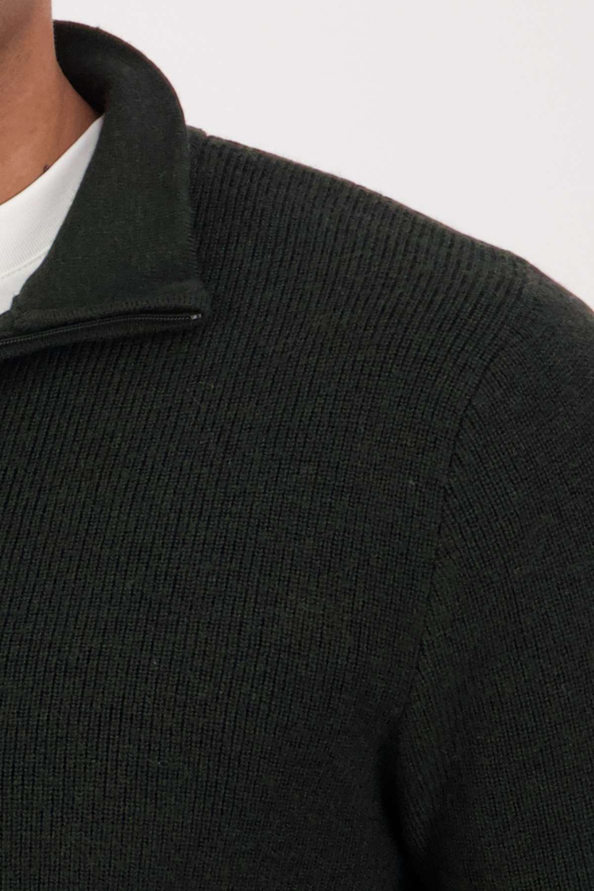 Close-up of a person wearing the Swanndri Otahu River Quarter Zip Merino Knit sweater with a short standing collar over a white shirt. Only the shoulder, upper chest, and part of the neck are visible.