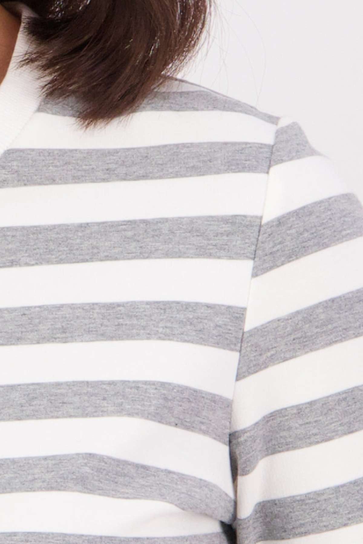 Close-up of a person wearing the Swanndri Papamoa Stripe Long Sleeve Tee, featuring horizontal gray and white stripes, a relaxed fit, and a white collar. Part of the person’s hair is visible at the top.