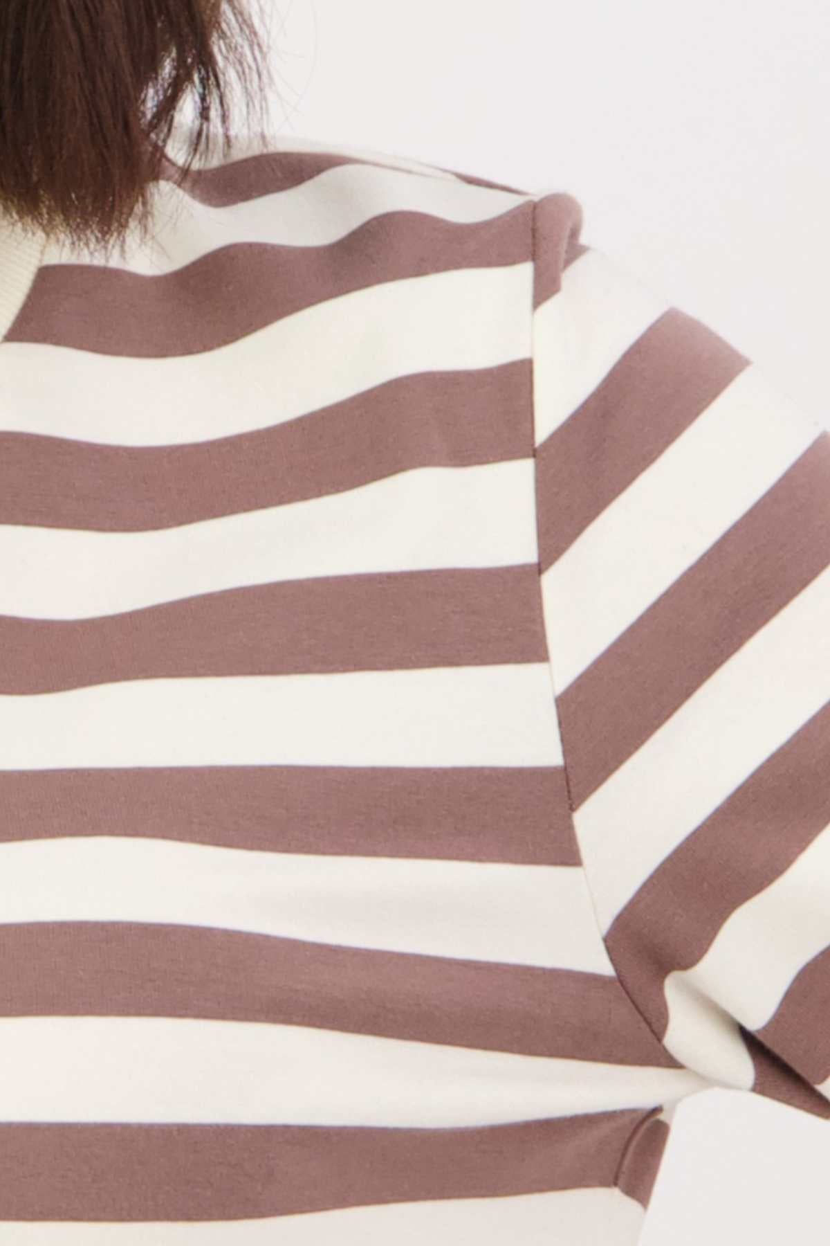 Close-up of a person's shoulder and arm wearing a Swanndri Papamoa Stripe Long Sleeve Tee featuring wide brown and white stripes. Made from cozy cotton elastane, this sweater's long sleeves are set against a plain white background.