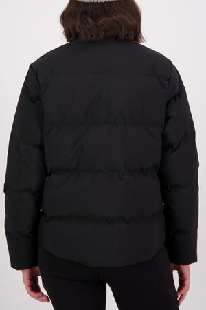 A person with shoulder-length dark brown hair is shown from the back wearing a black Swanndri Plume Down Jacket and black pants, standing against a plain white background.