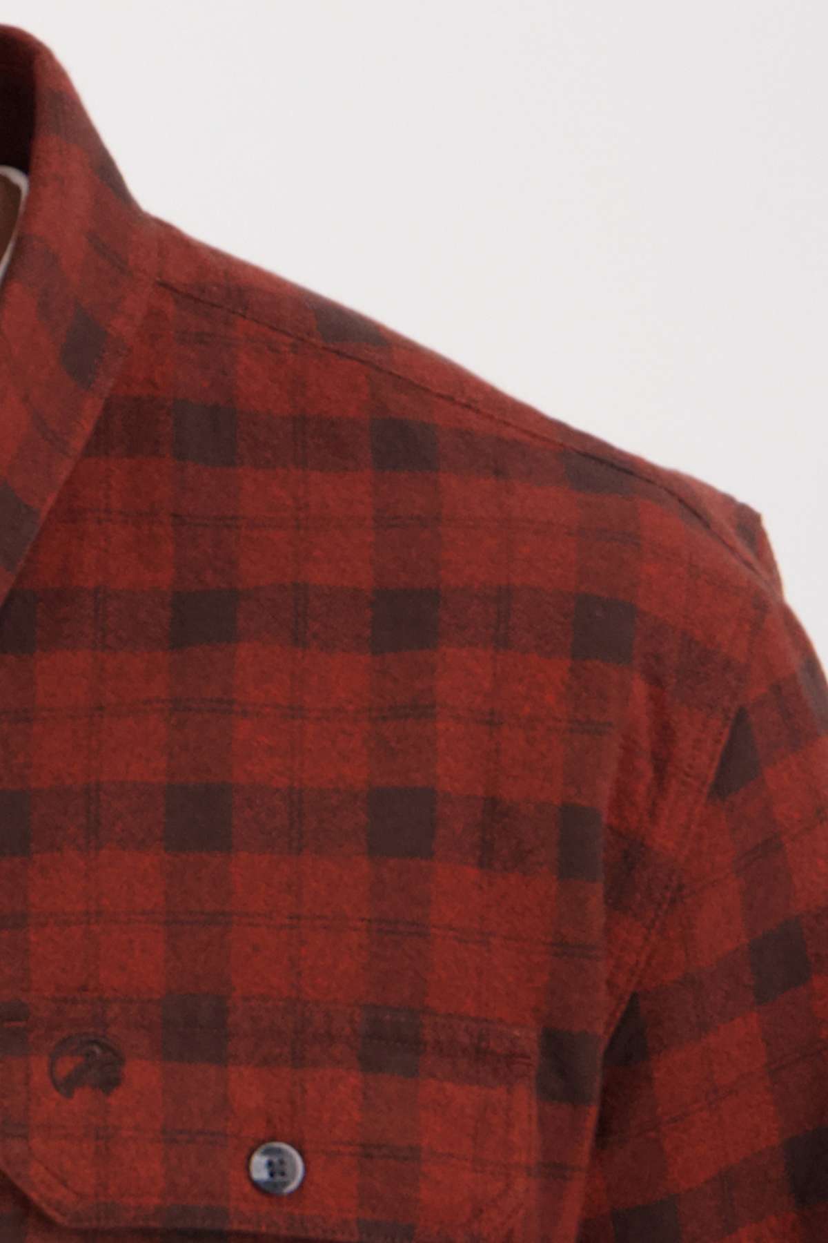 Close-up of a Swanndri Port Road Shirt in red and black plaid, highlighting the upper left shoulder area and part of the collar. Made from soft cotton, it includes buttoned chest pockets for style and practicality.
