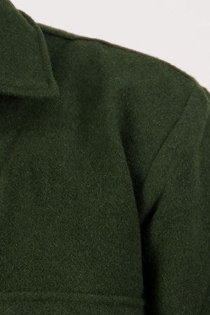 Close-up of the upper section of a dark green Swanndri Ranger Bush Shirt, highlighting the collar, shoulder seam, and fabric texture against a plain light background.