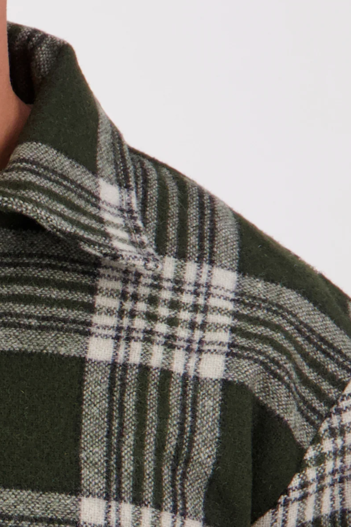 Close-up of the Swanndri Ranger Bush Shirt collar and shoulder in green and white plaid, highlighting the fabric texture and intersecting lines. Only part of the wearer’s neck and shoulder is visible.