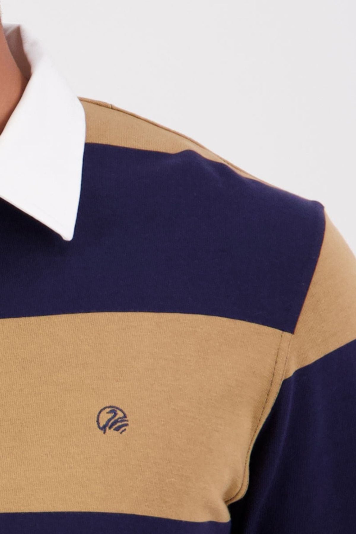 A close-up of a person wearing the Swanndri Ridgeway Rugby—a navy blue and tan striped cotton top with a white collar, featuring Swanndri embroidery and a small logo on the chest.