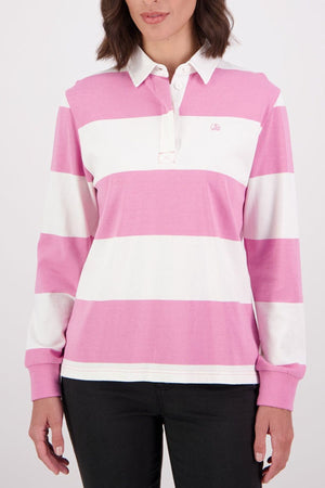 A woman wearing a Swanndri Ridgeway Womens Rugby with wide pink and white stripes, a white collar, and black pants stands against a plain light background.