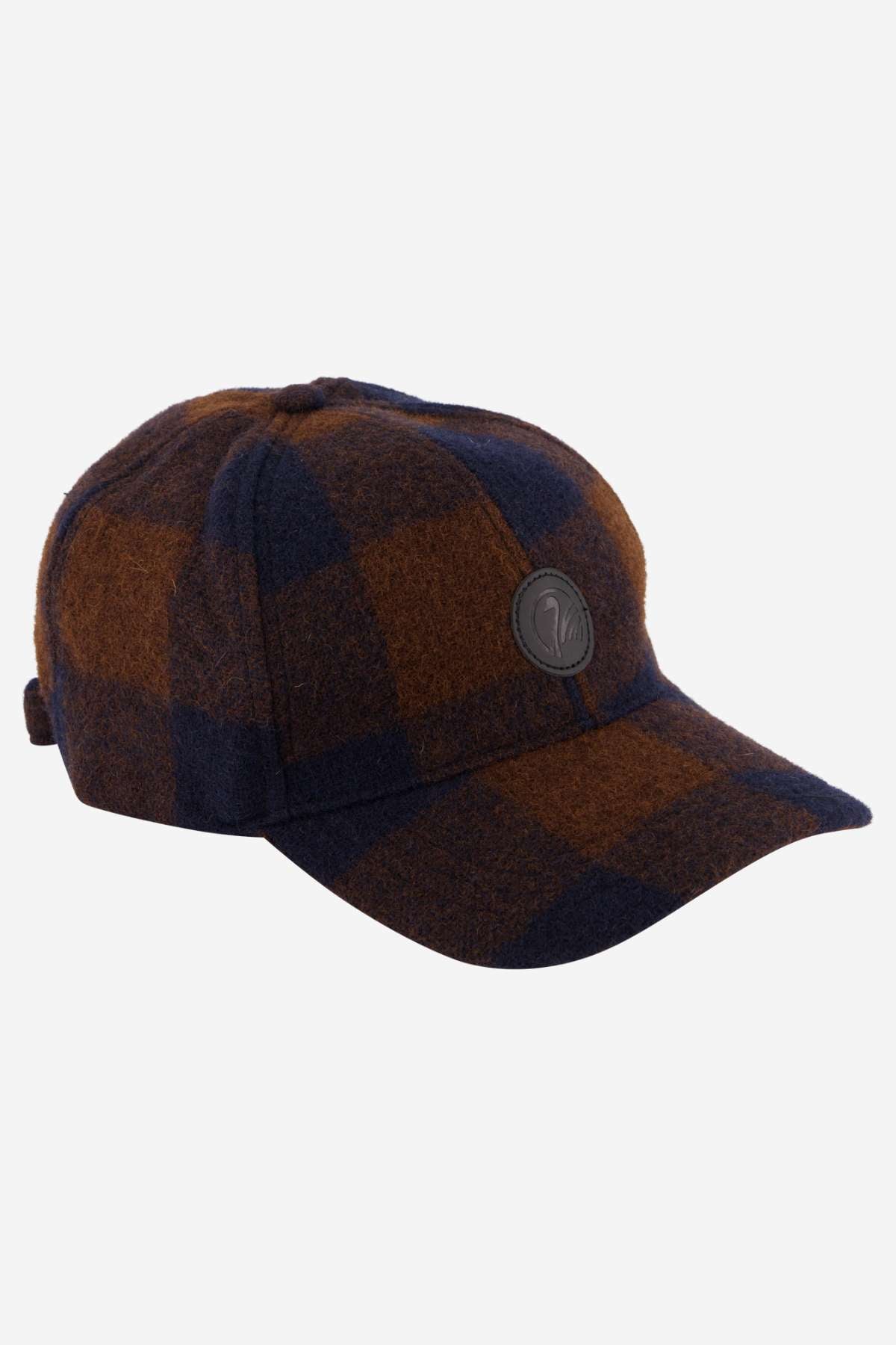 Introducing the Swanndri Swanni Wool Check Baseball Cap, showcasing a brown and dark blue checkered pattern with a stylish curved brim and a black circular logo on the front. It includes an adjustable buckle at the back, ensuring comfort and timeless style.