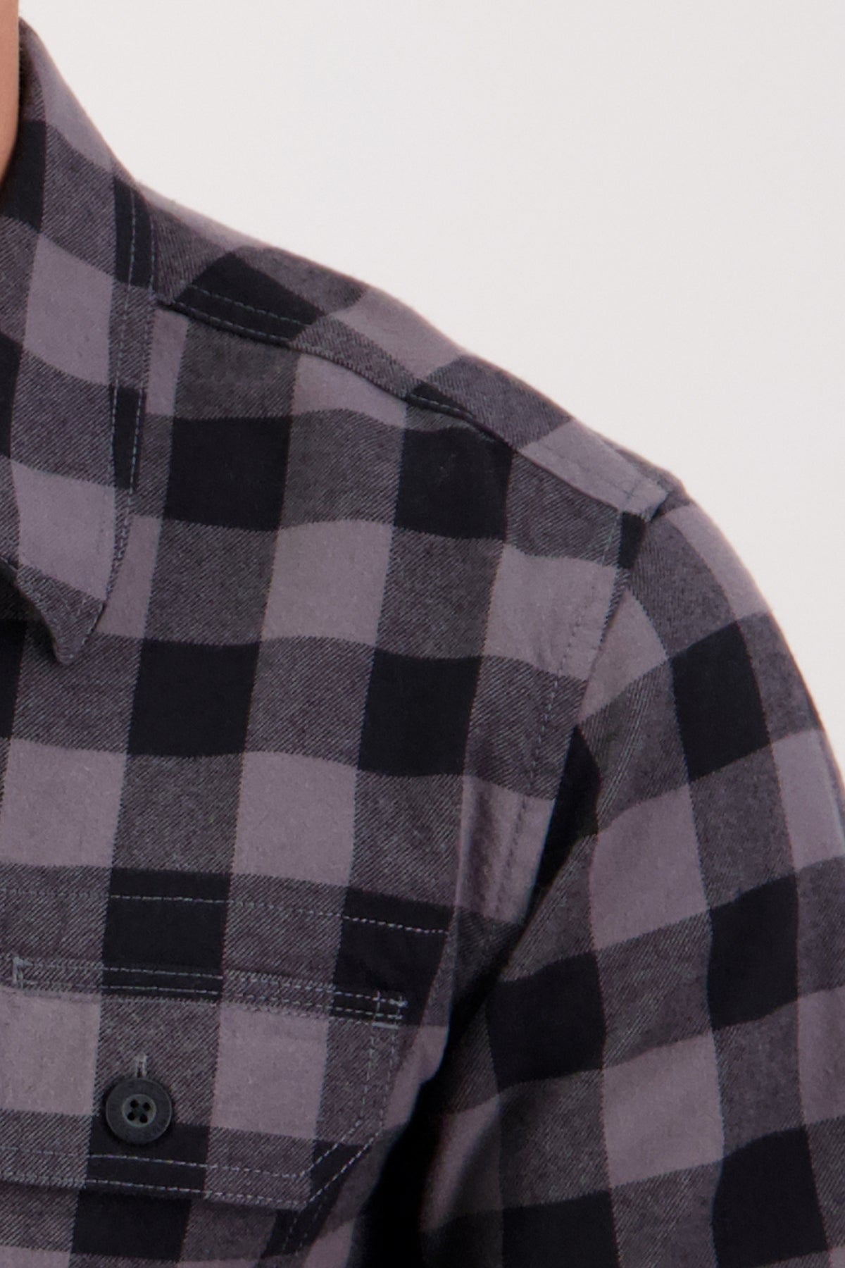 Close-up of the Swanndri Taranaki Tailor Shirt, a men's casual shirt in black and gray plaid with a front pocket and button detail.