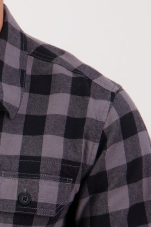 Close-up of the Swanndri Taranaki Tailor Shirt, a men's casual shirt in black and gray plaid with a front pocket and button detail.