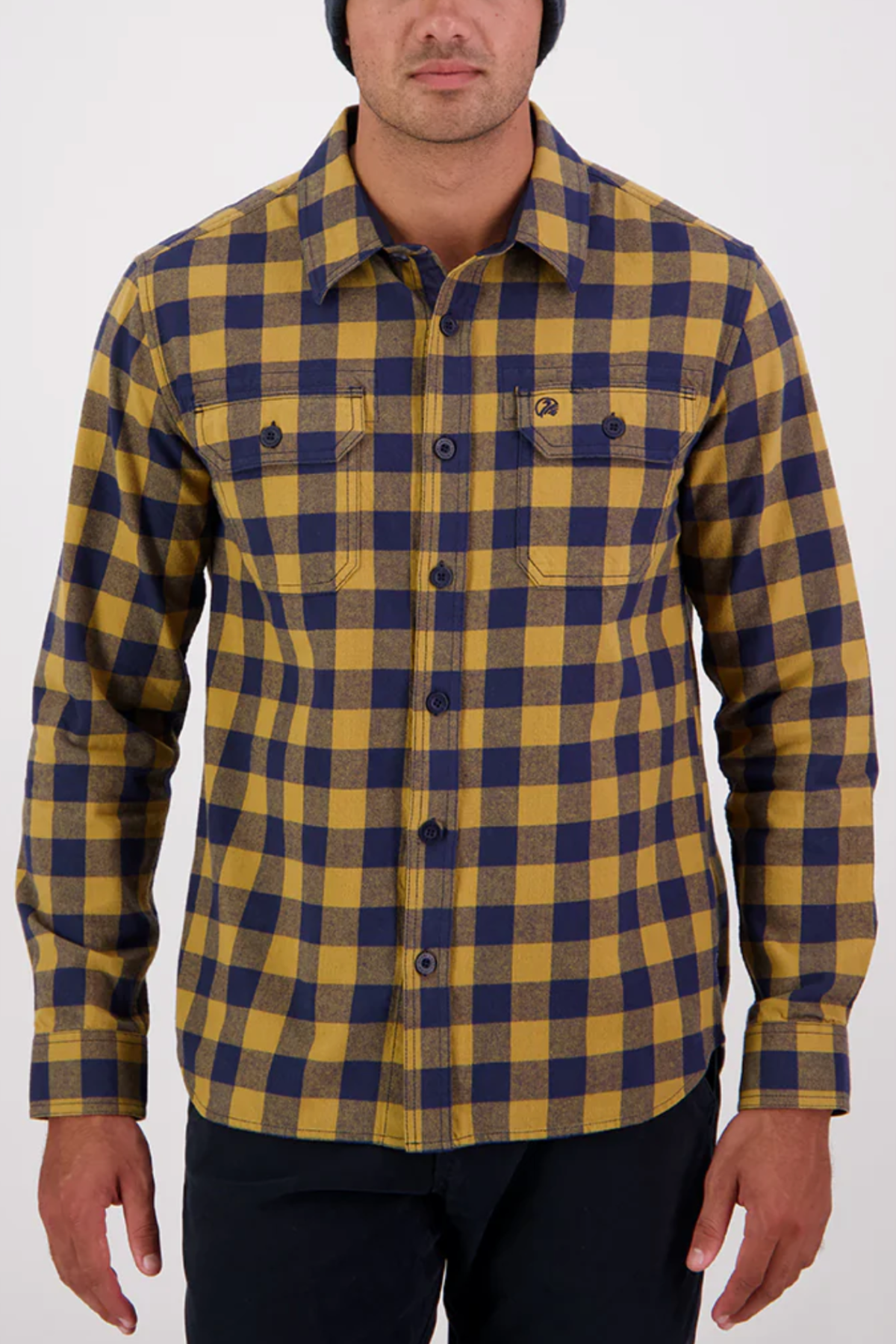 A person, head partially out of frame, stands against a plain light background in the Swanndri Taranaki Tailor Shirt—yellow and navy blue, with buttoned chest pockets and made from 100% cotton.