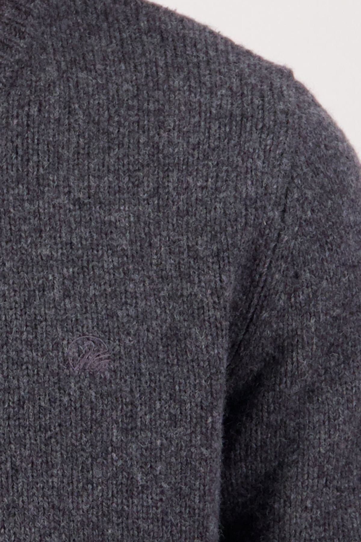 Close-up of the dark gray Swaandri Waylins Wool Knit Crew sweater, featuring a ribbed crew neck, soft lambswool knit for warmth and comfort, partial view of shoulder and upper sleeve, and a subtle chest logo.