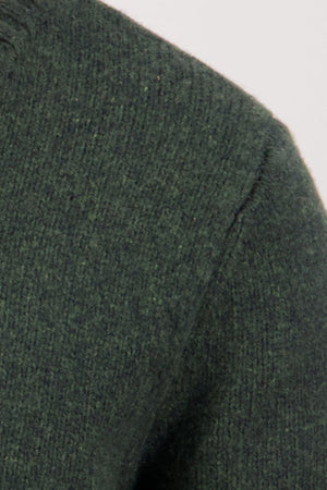 Close-up of the shoulder and sleeve of the Swaandri Waylins Wool Knit Crew in dark green, highlighting the textured stitching and durable wool knit against a plain light background.