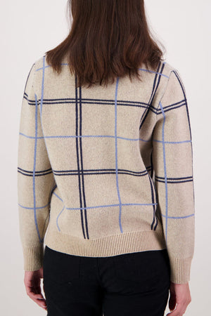A person with shoulder-length brown hair is seen from behind, wearing a Swanndri Yasmin Check Womens Knit sweater in blue and black plaid with black pants, against a plain light background.