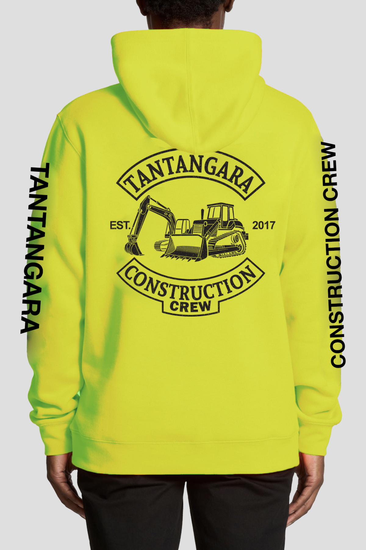 Person wearing the Tantangara Construction Crew Hoodie PRE-ORDER, featuring a bright yellow design, “TANTANGARA CONSTRUCTION CREW” and an excavator graphic on the back, plus bold black sleeve text for standout style.