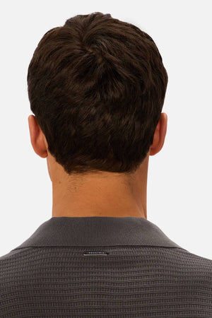 A man with short, dark brown hair is shown from behind, wearing the Industrie The Alicante Polo in textured dark gray against a plain light background.